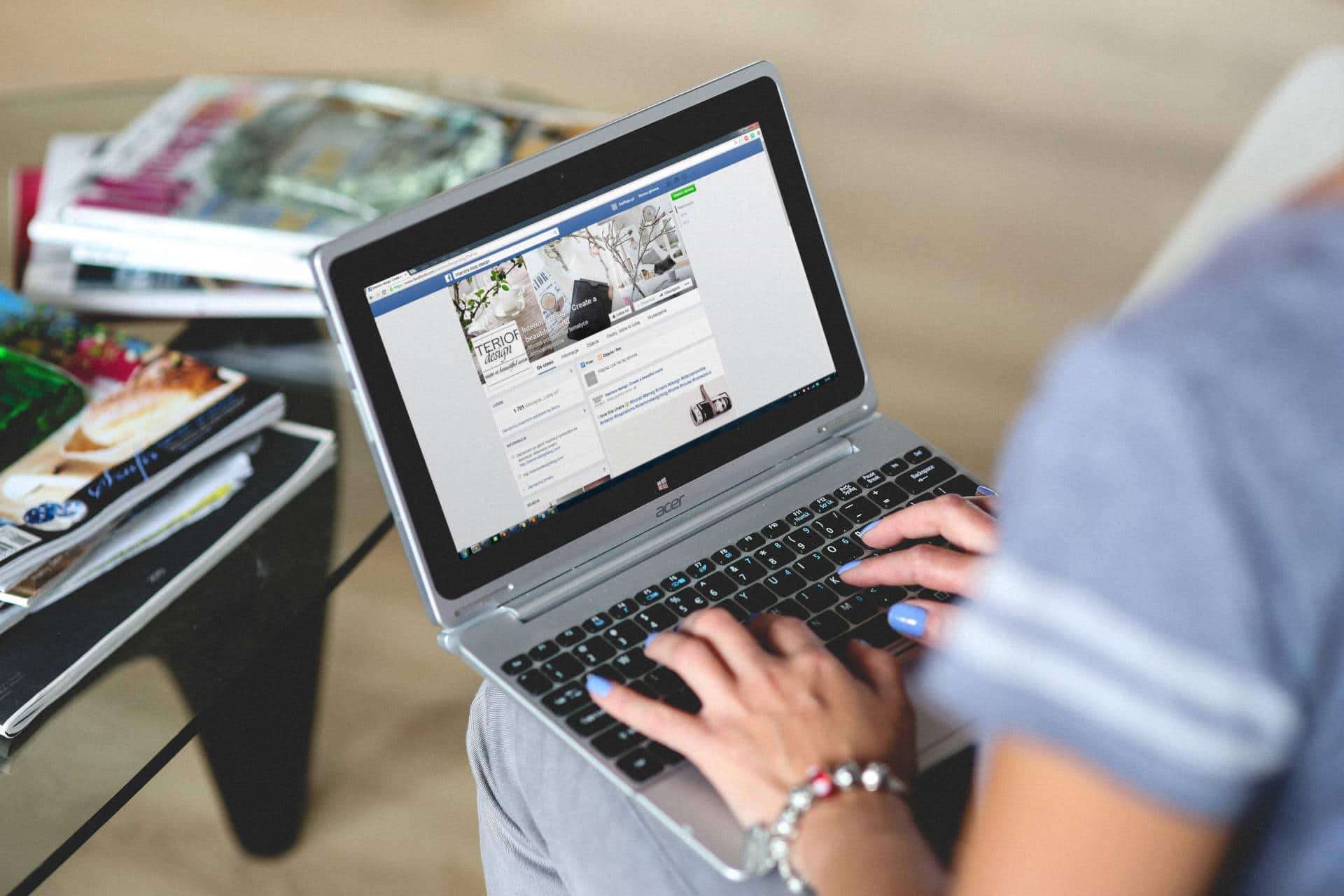A woman creates a Facebook post on a laptop